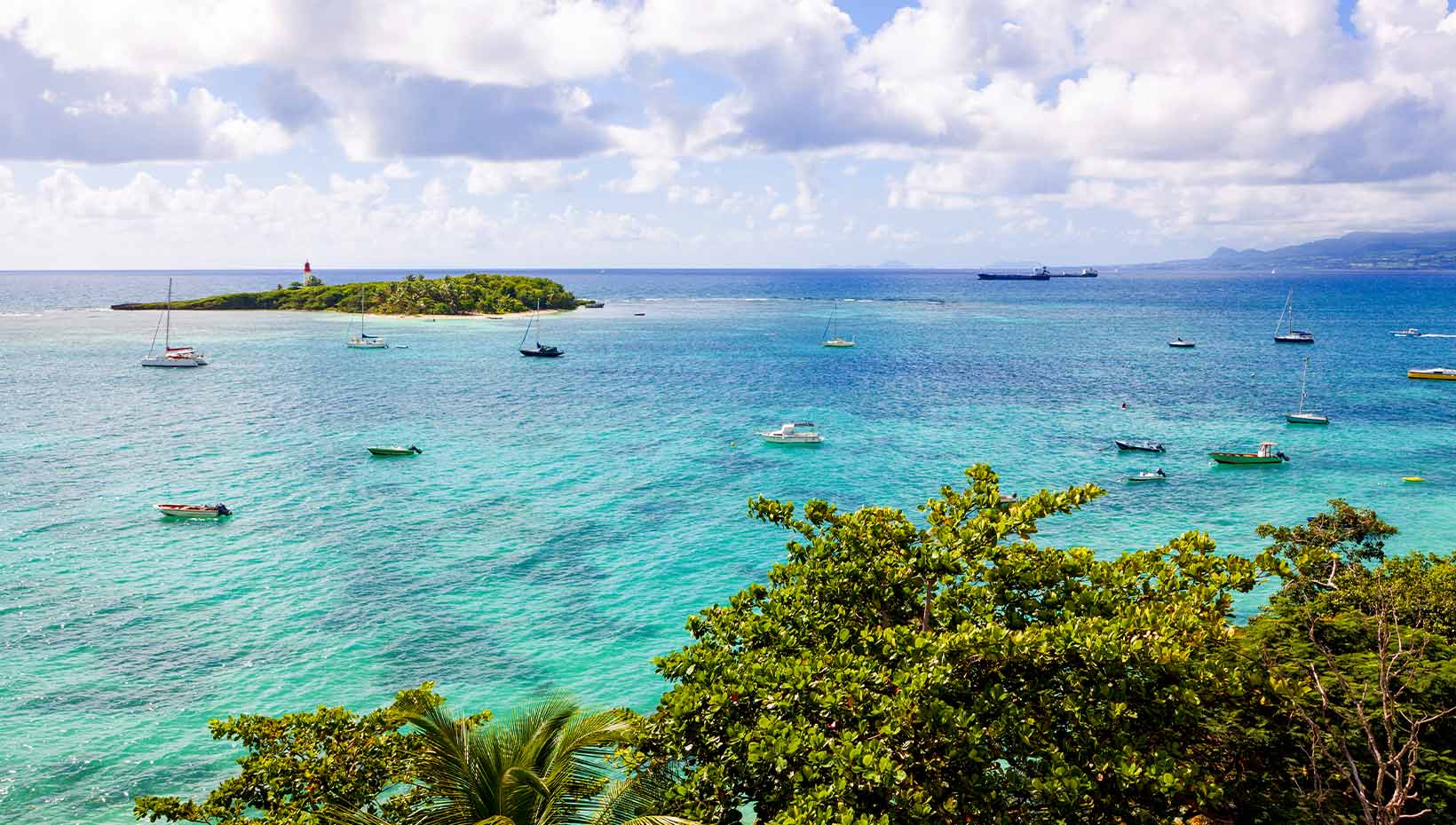 Turquoise waters with sailboats near a tropical island | MSC Cruises Turquoise waters with sailboats near a tropical island | MSC Cruises