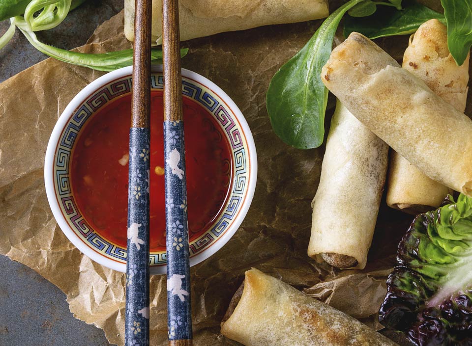 Spring rolls served with sweet chili sauce and chopsticks on a rustic table setting | MSC Cruises Spring rolls served with sweet chili sauce and chopsticks on a rustic table setting | MSC Cruises