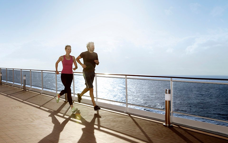 Two people jogging on a sunlit cruise ship deck with ocean views | MSC Cruises Two people jogging on a sunlit cruise ship deck with ocean views | MSC Cruises