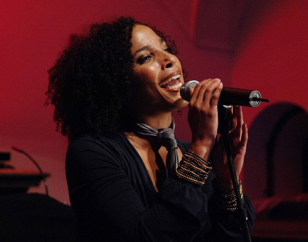 A performer singing on stage with a microphone under warm red lighting | MSC Cruises A performer singing on stage with a microphone under warm red lighting | MSC Cruises