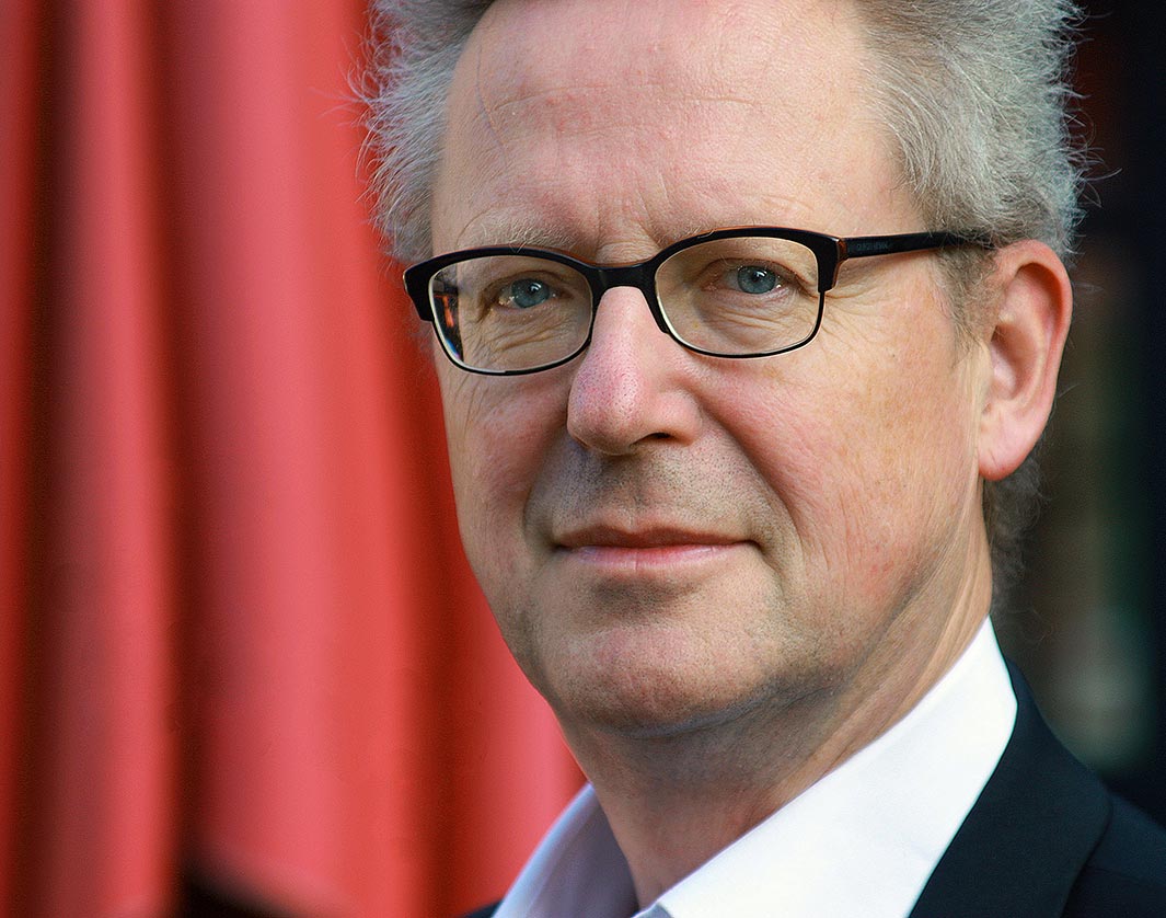 A man in formal attire with a red curtain backdrop | MSC Cruises A man in formal attire with a red curtain backdrop | MSC Cruises