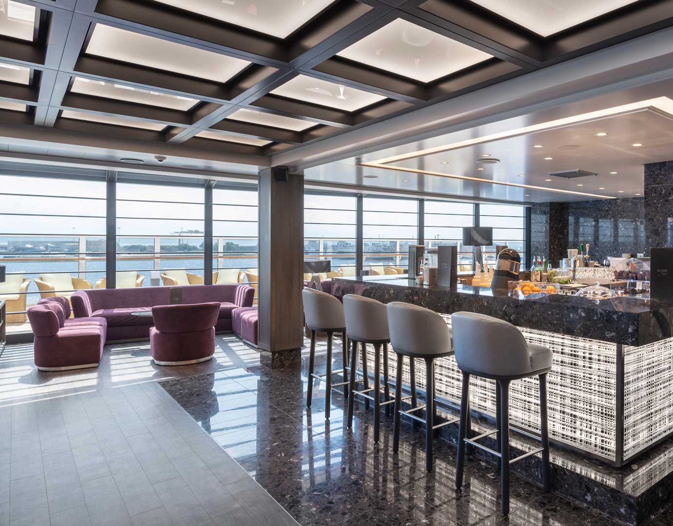 Elegant lounge with plush seating and panoramic windows aboard MSC Seaview | MSC Cruises Elegant lounge with plush seating and panoramic windows aboard MSC Seaview | MSC Cruises