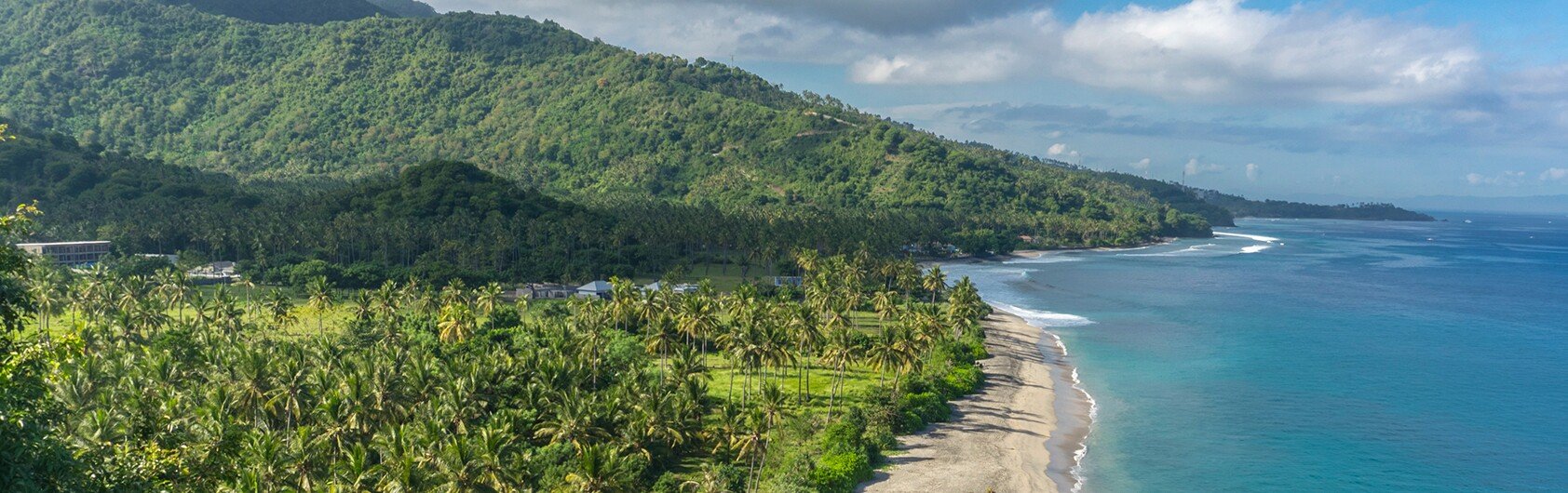 A tropical coastline with lush green hills and turquoise waters | MSC Cruises